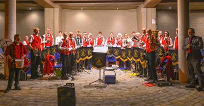 people in red waistcoats and white shirts in semi circle with brass instruments