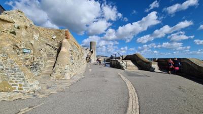 photograph of Gun Cliff walk and blue lias walls on a bright sunny day with people walking along the promenade